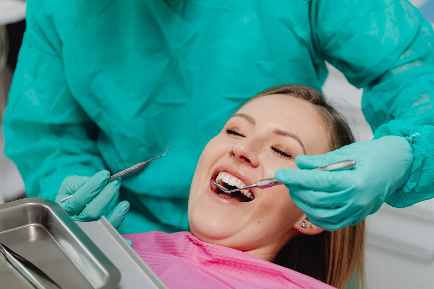 A dentist performing an examination on a smiling patient in a dental treatment room.