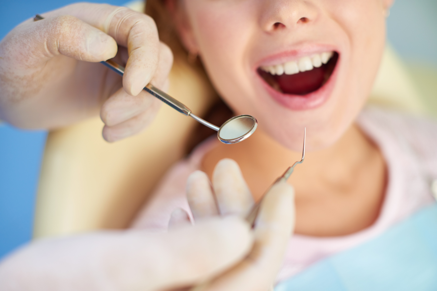 A dentist examining a young patient's teeth with diagnostic tools in a dental office.