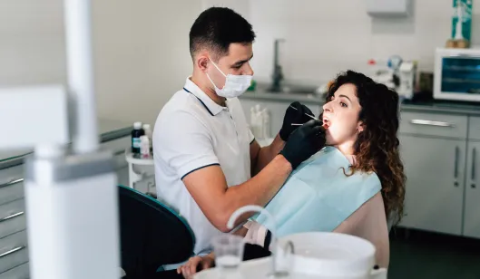 A dentist examining a patient's teeth in a modern treatment room at SmileVibe Dentistry in Renton, WA.