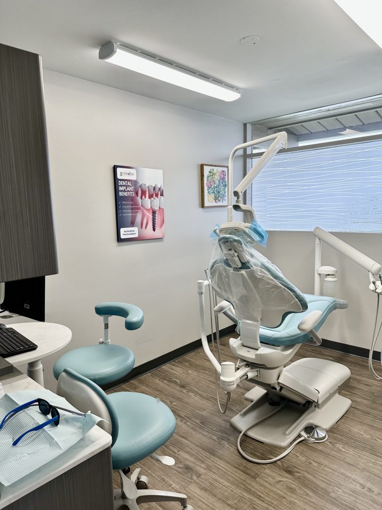 A dental treatment room at SmileVibe Dentistry featuring an examination chair, dental equipment, and a computer station.