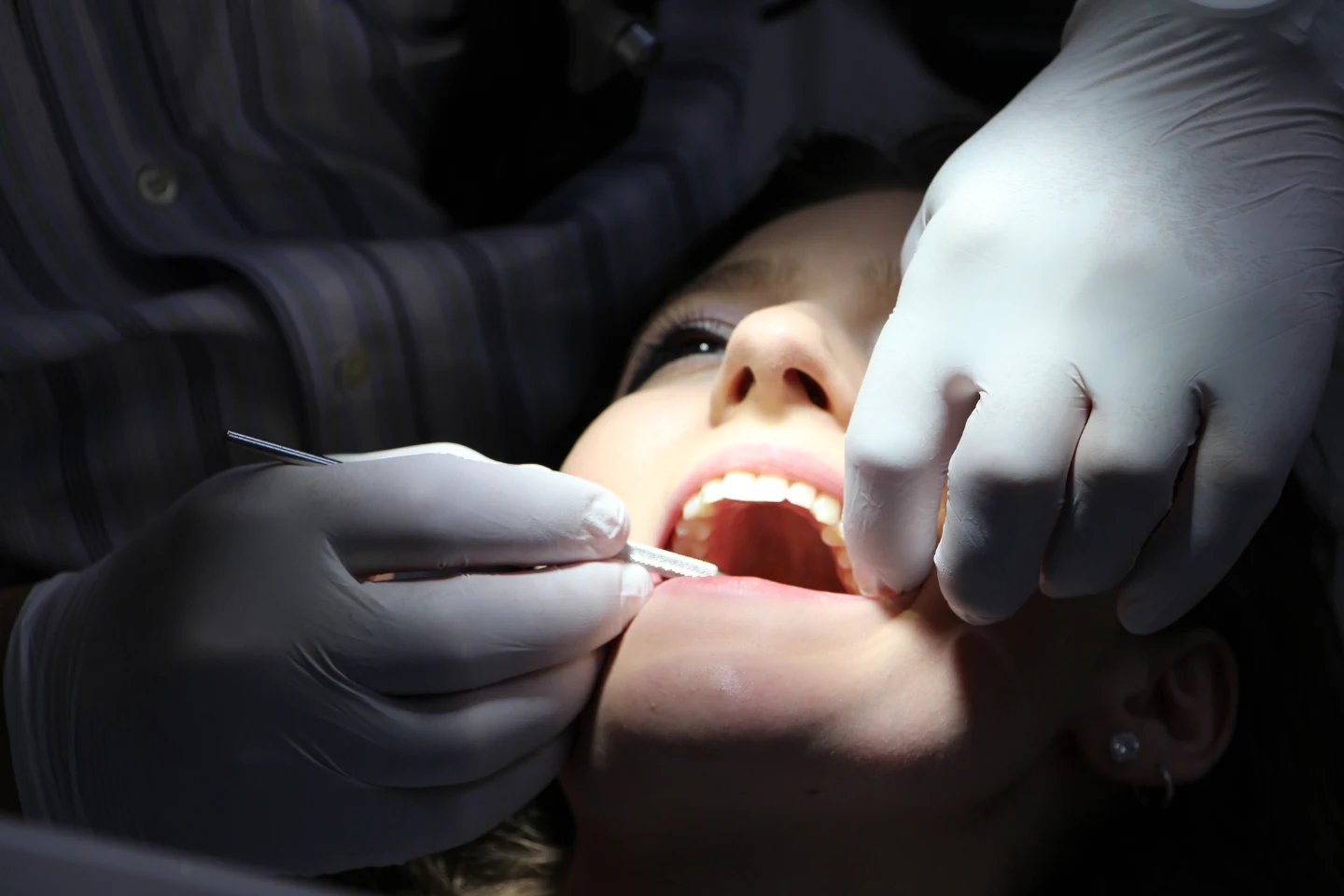 A dentist in Renton examining a patient's teeth with dental tools while the patient lies back in a treatment chair.