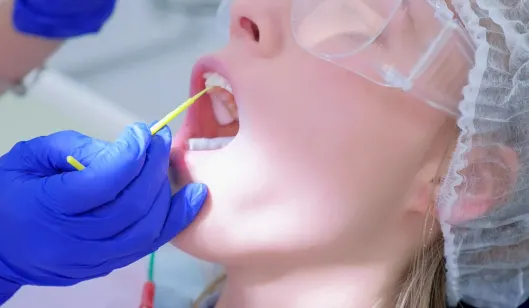 A dentist in Renton examining a child's teeth using a dental tool in a clinical setting.
