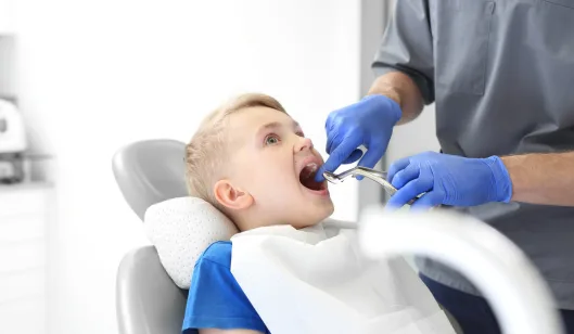 A dentist in Renton examining a child's mouth with dental tools in a bright treatment room.